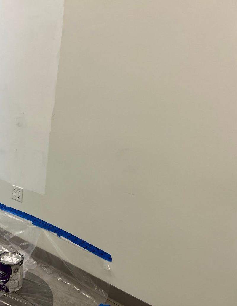 The same wall patched and primed, floor protected